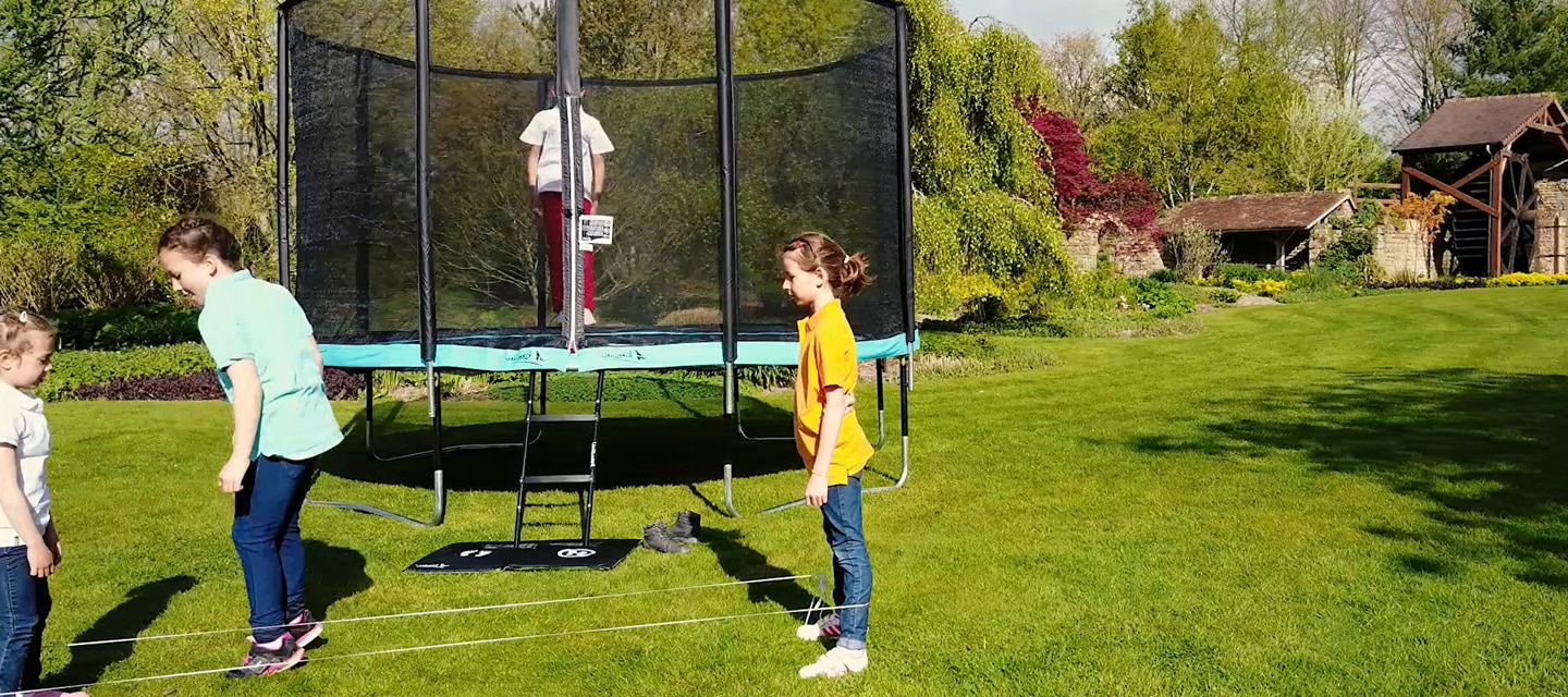 enfants qui s'amuse autour du trampoline de jardin punchi dans un jardin