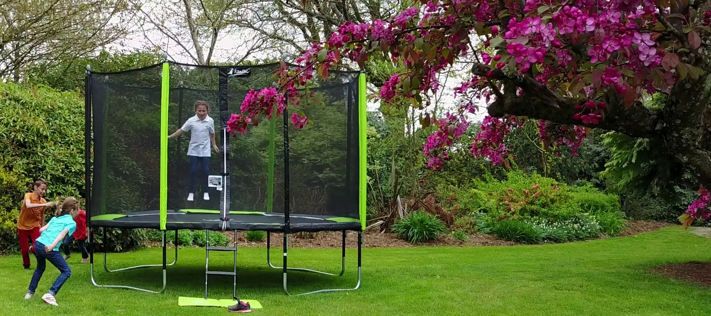enfants qui jouent et sautent autour d'un trampoline de jardin jumpi dans un parc