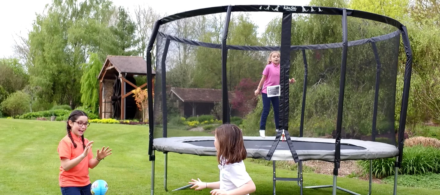 enfants qui s'amuse autour du trampoline de jardin famili dans un jardin